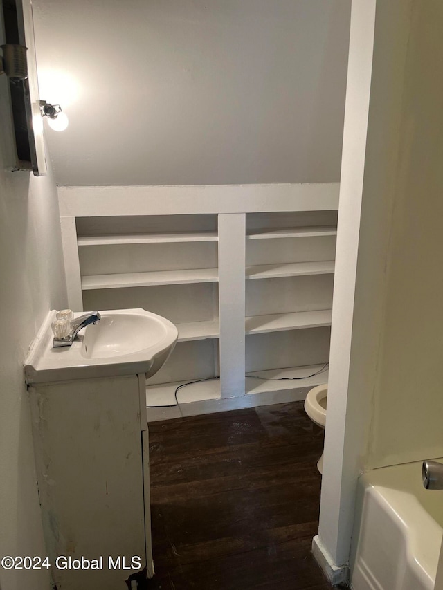 bathroom with hardwood / wood-style flooring, a tub, vanity, and toilet