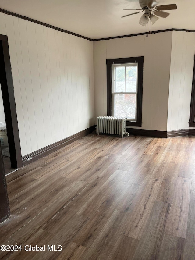 unfurnished room featuring hardwood / wood-style floors, crown molding, ceiling fan, and radiator heating unit