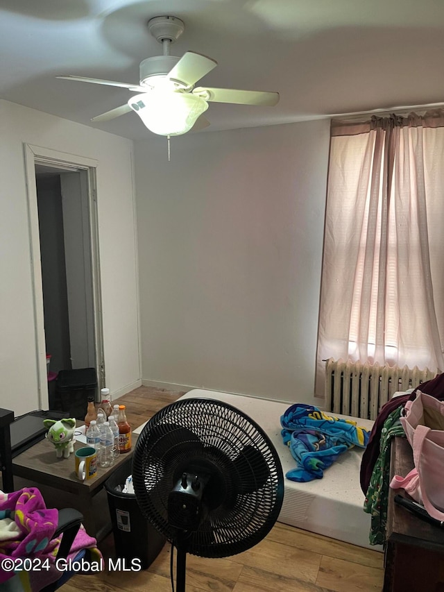 bedroom featuring ceiling fan, radiator heating unit, and light hardwood / wood-style flooring