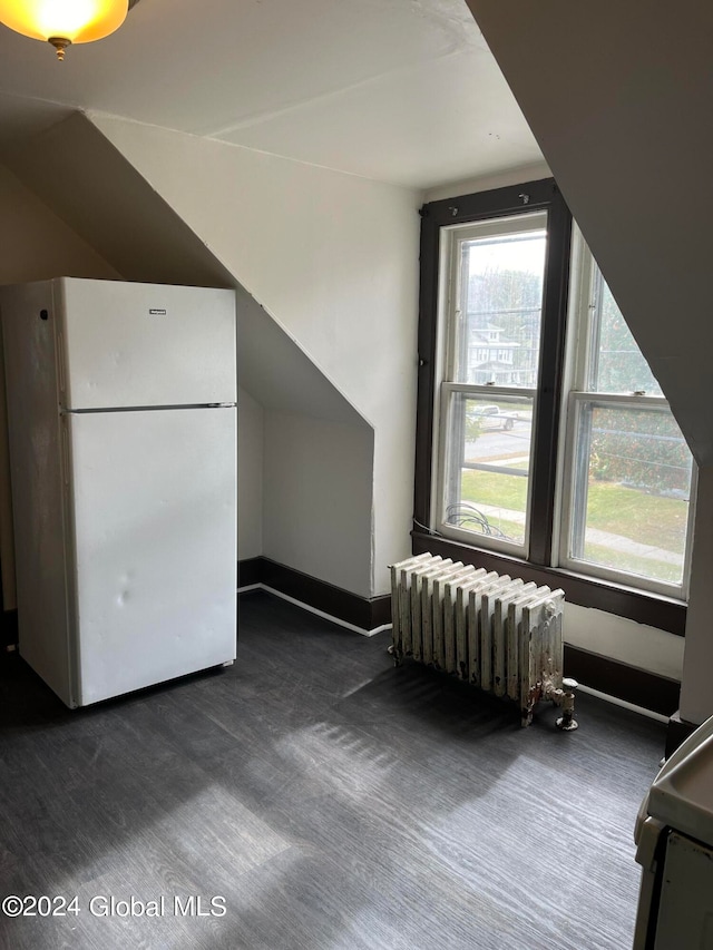 additional living space with dark colored carpet, vaulted ceiling, and radiator heating unit