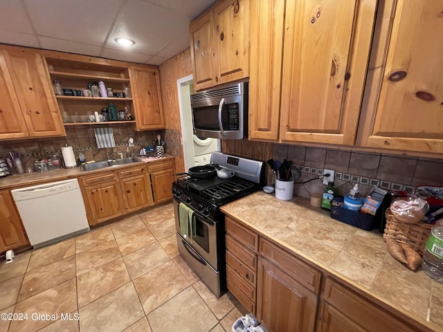 kitchen with tile counters, sink, light tile patterned floors, appliances with stainless steel finishes, and tasteful backsplash