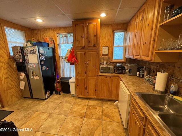 kitchen featuring tile countertops, white dishwasher, sink, stainless steel fridge with ice dispenser, and a paneled ceiling