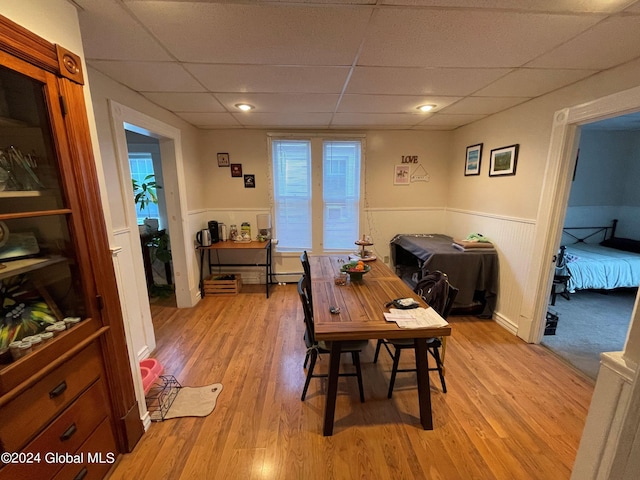 dining space featuring a drop ceiling and light wood-type flooring