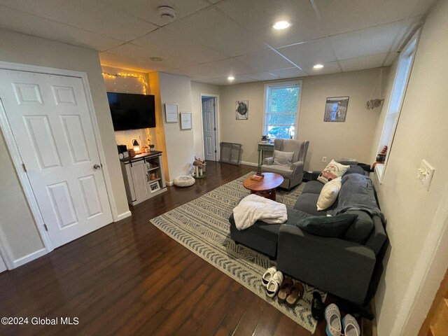 living room featuring dark hardwood / wood-style flooring and a drop ceiling