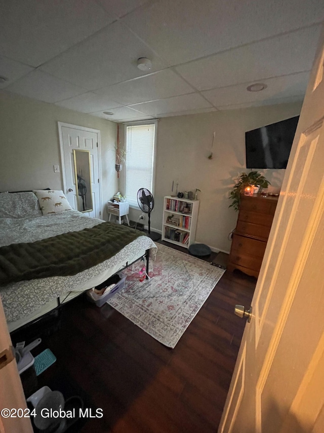 bedroom with a paneled ceiling and dark hardwood / wood-style flooring