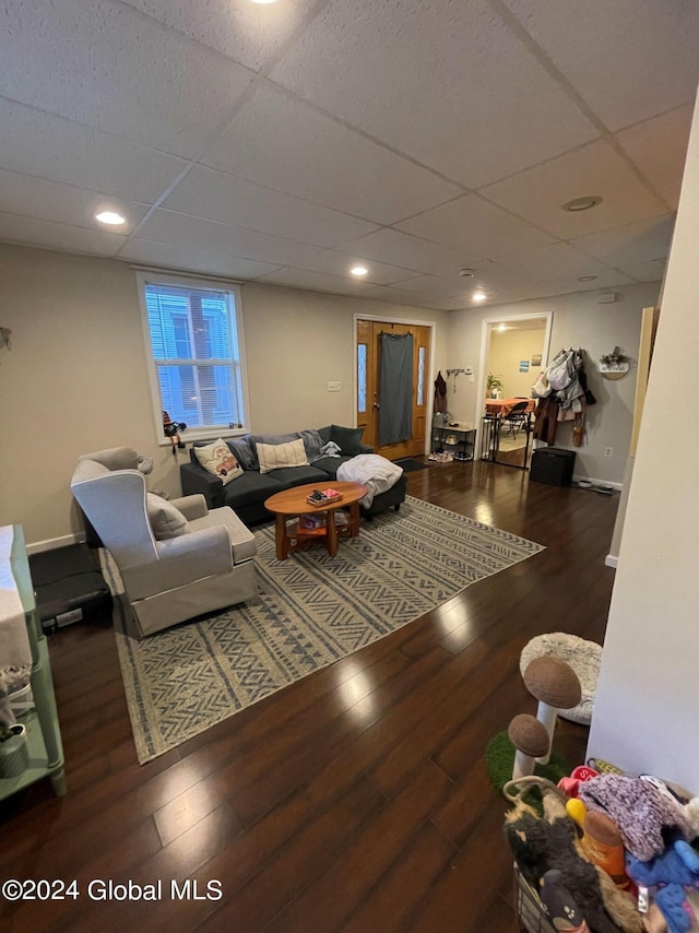 living room featuring dark hardwood / wood-style flooring and a drop ceiling