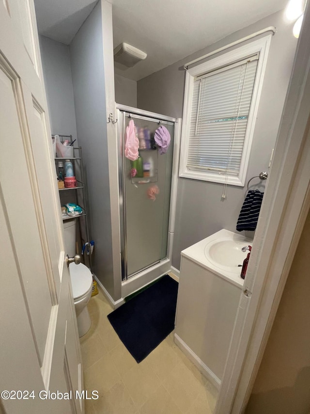 bathroom featuring a shower with door, toilet, and vanity