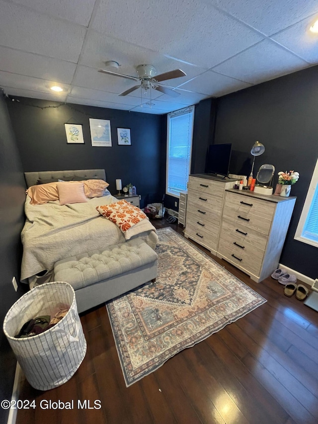 bedroom with dark wood-type flooring, a paneled ceiling, and ceiling fan