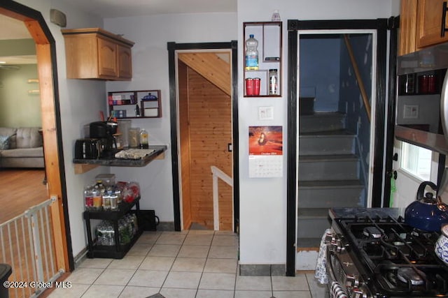 kitchen with light tile patterned flooring, black gas stove, and a barn door