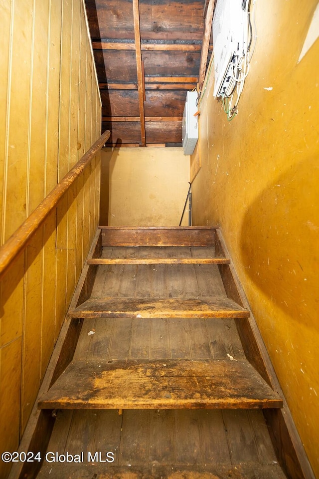 stairway featuring wooden walls