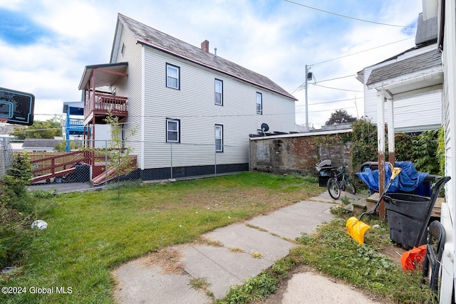 view of home's exterior with a balcony and a yard