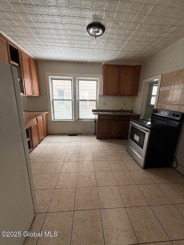 kitchen featuring white refrigerator, light tile patterned flooring, and electric range