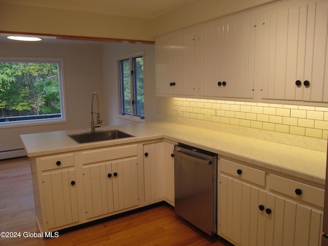 kitchen featuring a peninsula, stainless steel dishwasher, light countertops, and a sink