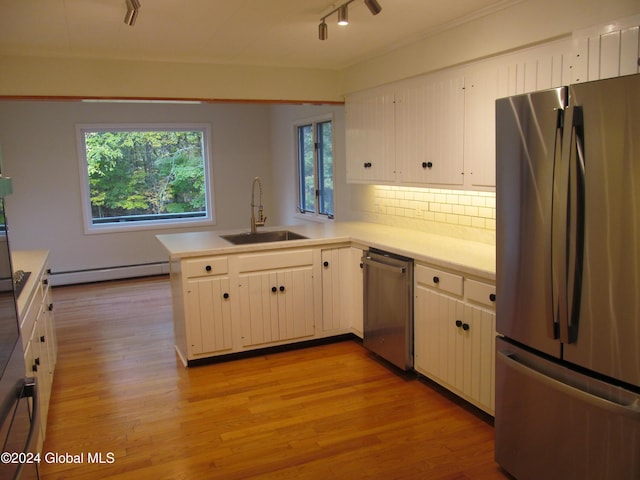 kitchen featuring light countertops, track lighting, a sink, a baseboard heating unit, and appliances with stainless steel finishes