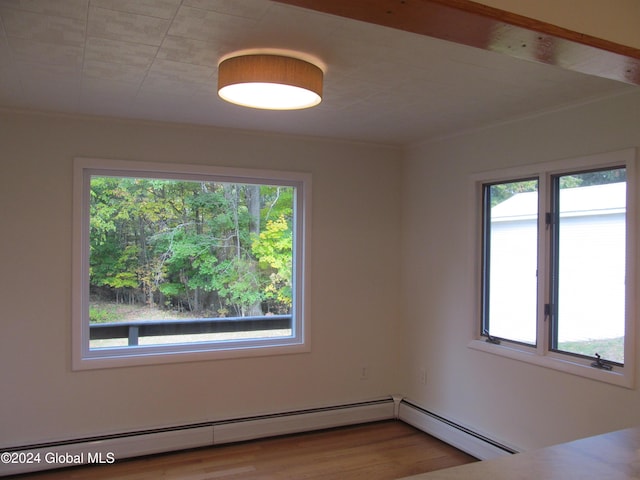 spare room with baseboard heating, wood finished floors, and plenty of natural light