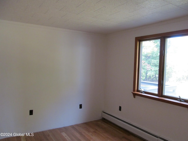 empty room with hardwood / wood-style flooring and a baseboard radiator