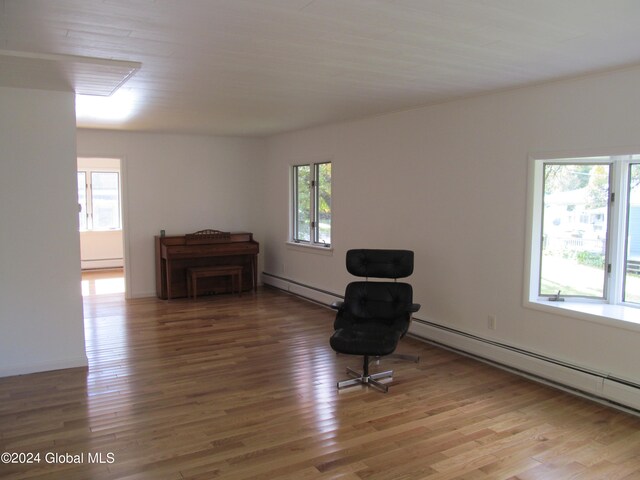 sitting room with baseboard heating, wood-type flooring, and plenty of natural light