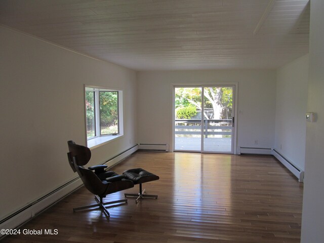 sitting room featuring a baseboard heating unit, wood-type flooring, and plenty of natural light