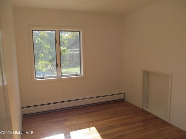 empty room featuring a baseboard radiator and wood finished floors