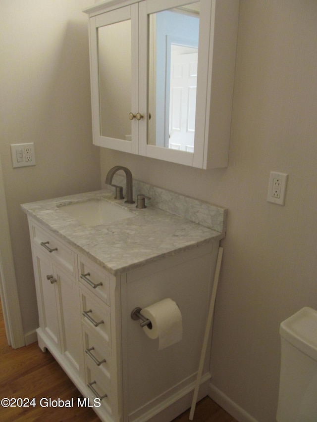 bathroom with baseboards, wood finished floors, toilet, and vanity