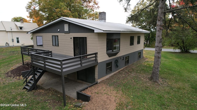 rear view of house with a lawn, a chimney, and a deck