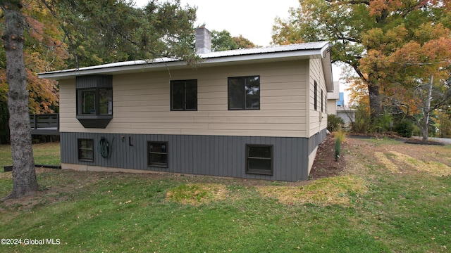 rear view of property featuring a chimney and a yard