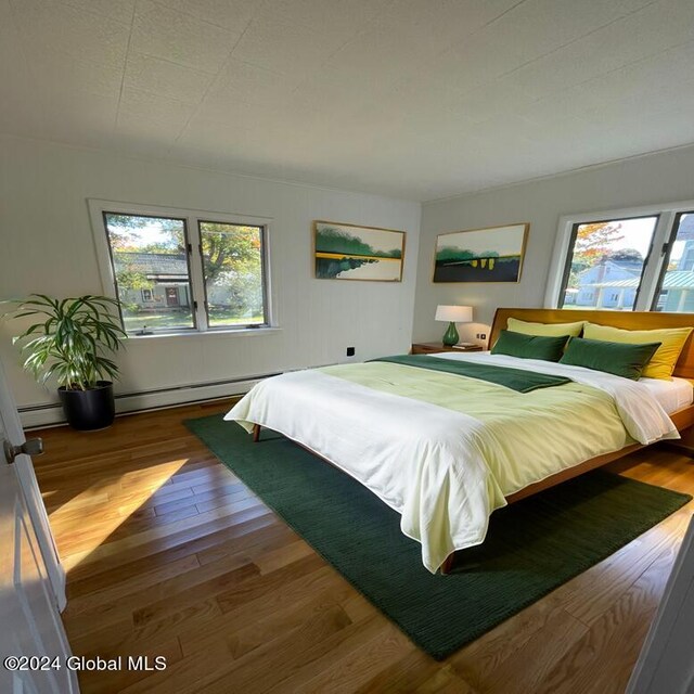 bedroom with baseboard heating and dark hardwood / wood-style floors