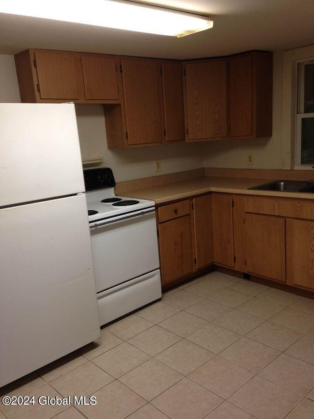 kitchen with white appliances, light tile patterned flooring, and sink