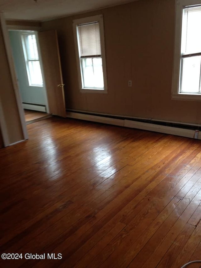 empty room featuring hardwood / wood-style floors and a baseboard radiator