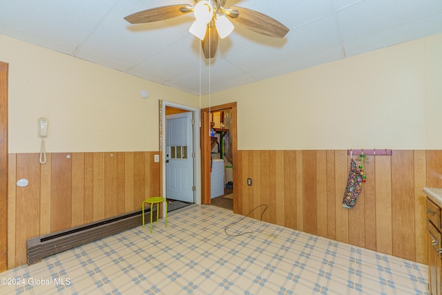 interior space featuring ceiling fan and wood walls