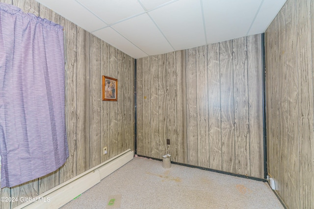 empty room with wooden walls and a baseboard heating unit