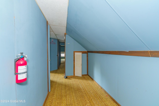 corridor with light carpet and lofted ceiling