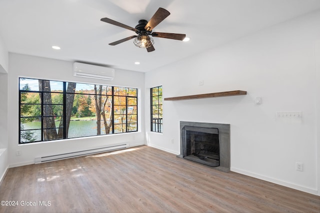 unfurnished living room featuring wood-type flooring, a wall unit AC, baseboard heating, and ceiling fan