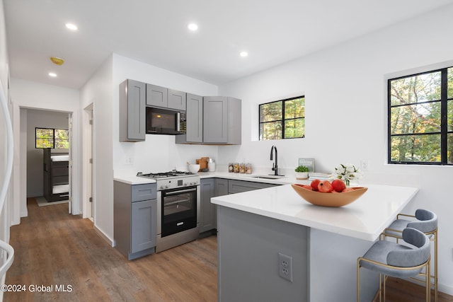 kitchen with kitchen peninsula, stainless steel gas stove, a wealth of natural light, and sink