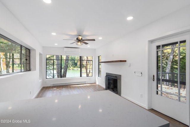 unfurnished living room with ceiling fan, a baseboard heating unit, dark hardwood / wood-style flooring, and a wall mounted AC