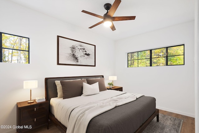 bedroom featuring dark hardwood / wood-style flooring, multiple windows, and ceiling fan