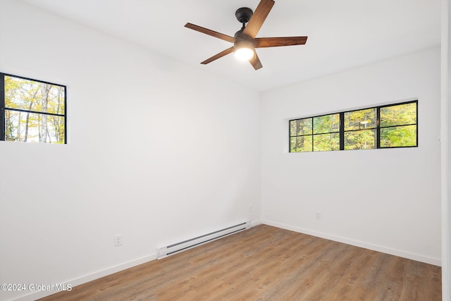 spare room featuring ceiling fan, light wood-type flooring, baseboard heating, and a wealth of natural light