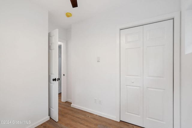 unfurnished bedroom with ceiling fan, a closet, and hardwood / wood-style flooring