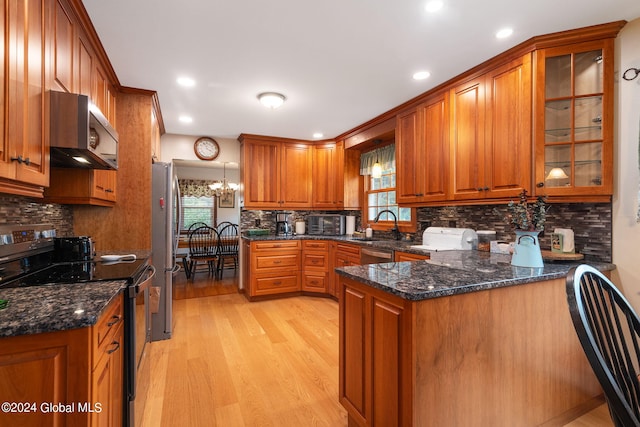 kitchen with kitchen peninsula, appliances with stainless steel finishes, light hardwood / wood-style flooring, dark stone countertops, and ventilation hood