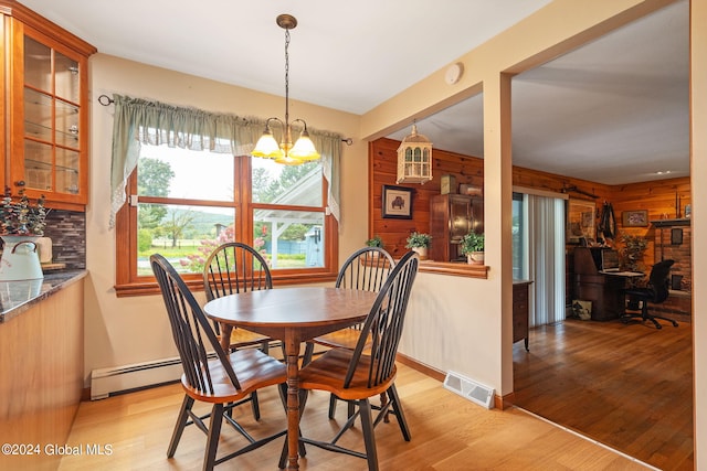 dining room featuring a notable chandelier, wood walls, and light wood-type flooring