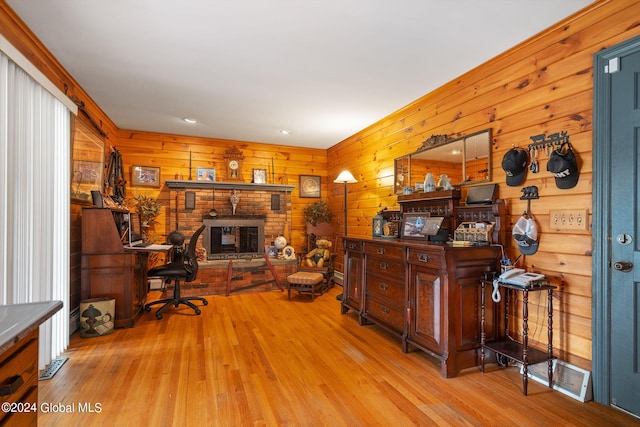 office space featuring wooden walls, a fireplace, and light wood-type flooring