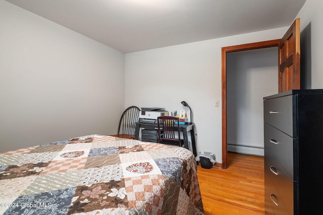 bedroom featuring a baseboard heating unit and light hardwood / wood-style floors