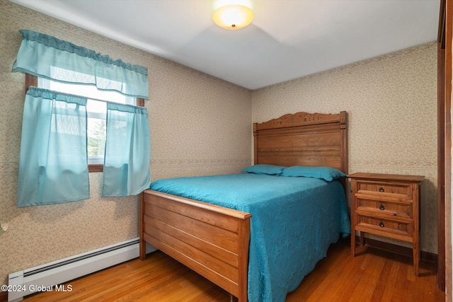 bedroom featuring hardwood / wood-style flooring and baseboard heating