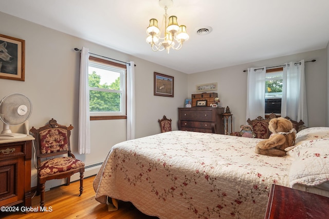 bedroom with a notable chandelier and light wood-type flooring