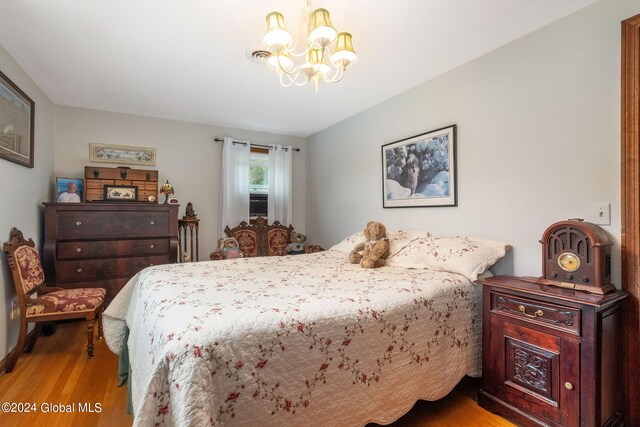 bedroom with a notable chandelier and light wood-type flooring