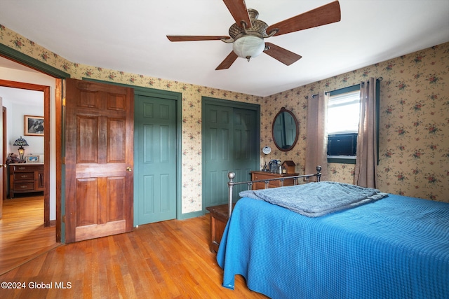 bedroom featuring multiple closets, light hardwood / wood-style flooring, and ceiling fan