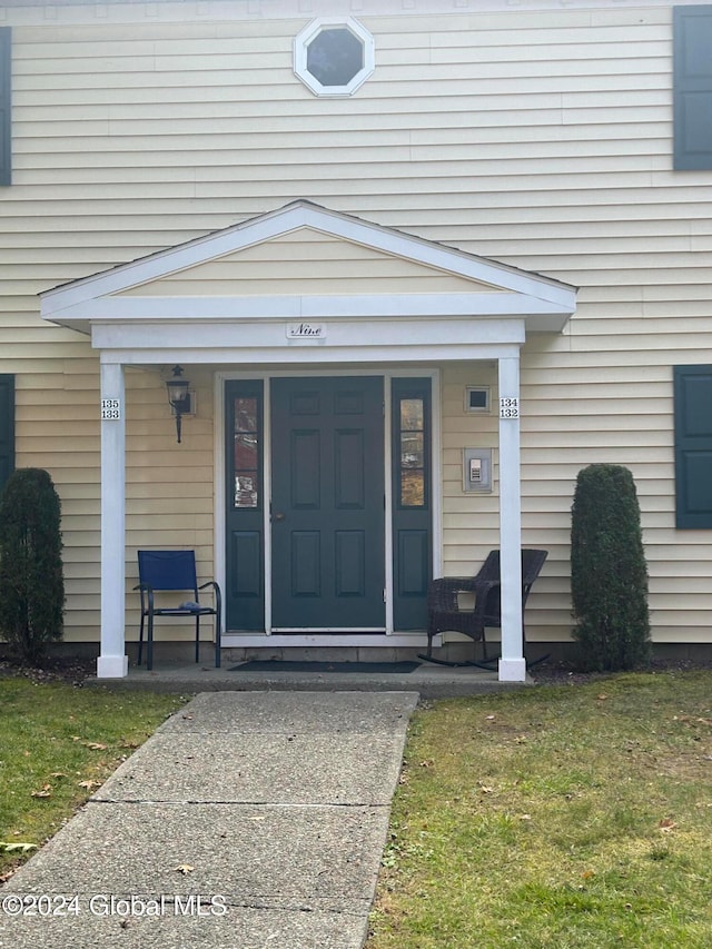 property entrance with a porch and a lawn