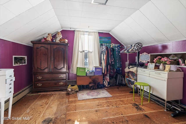 bedroom with dark hardwood / wood-style floors, baseboard heating, wooden walls, and vaulted ceiling