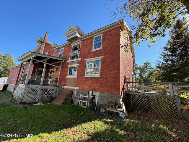 back of property with a yard and a deck