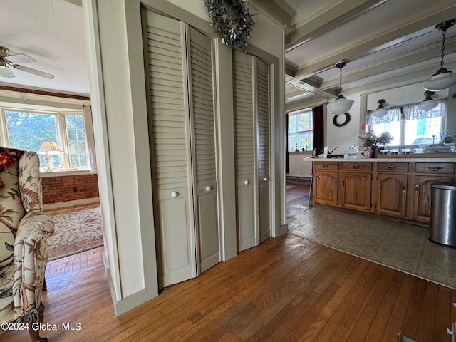 corridor with light hardwood / wood-style flooring, beamed ceiling, and crown molding